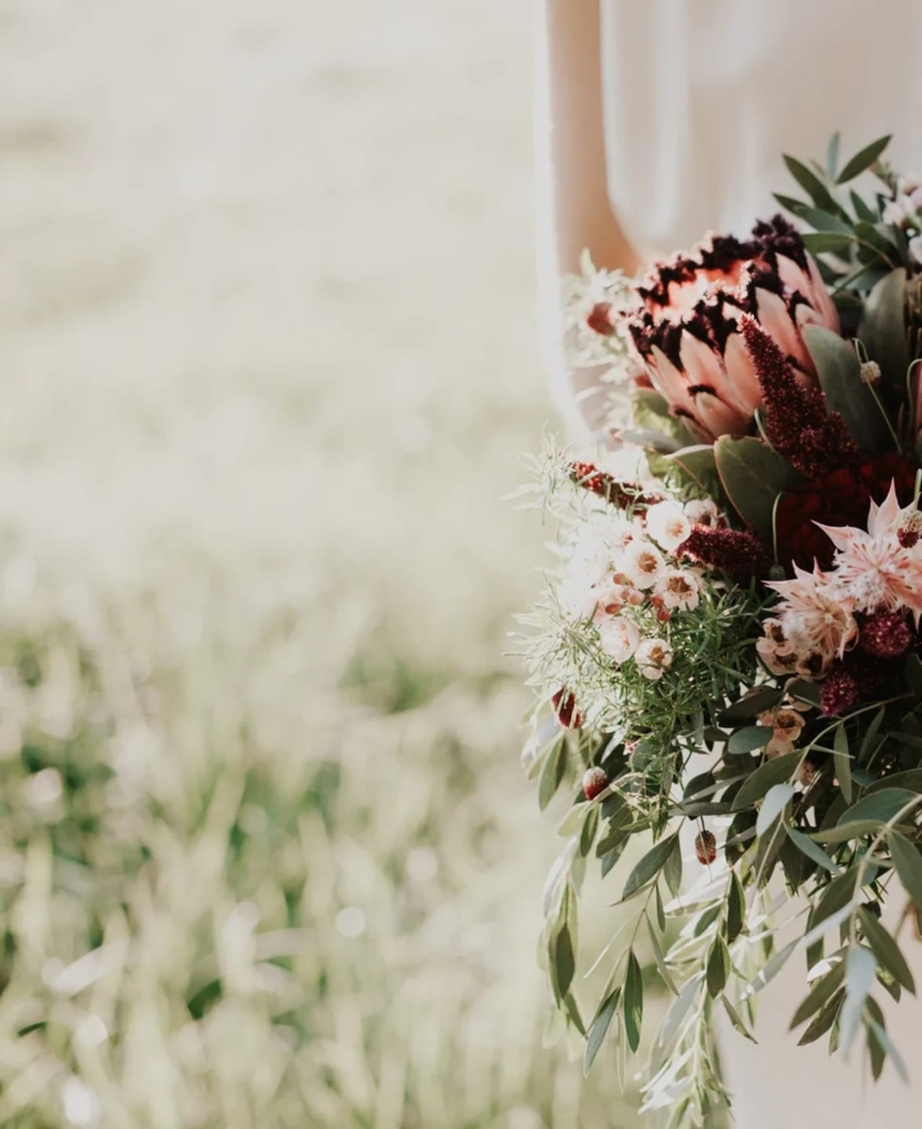 Bride holding eco-friendly wedding bouquet with local proteas, seasonal blooms and cascading greenery.