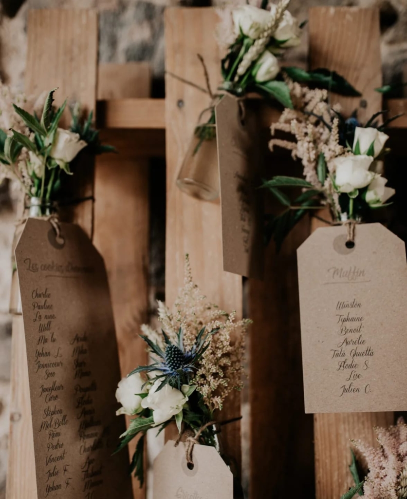 Plans de table habillés de fleurs blanches, gypsophile et feuillage sur support bois naturel.