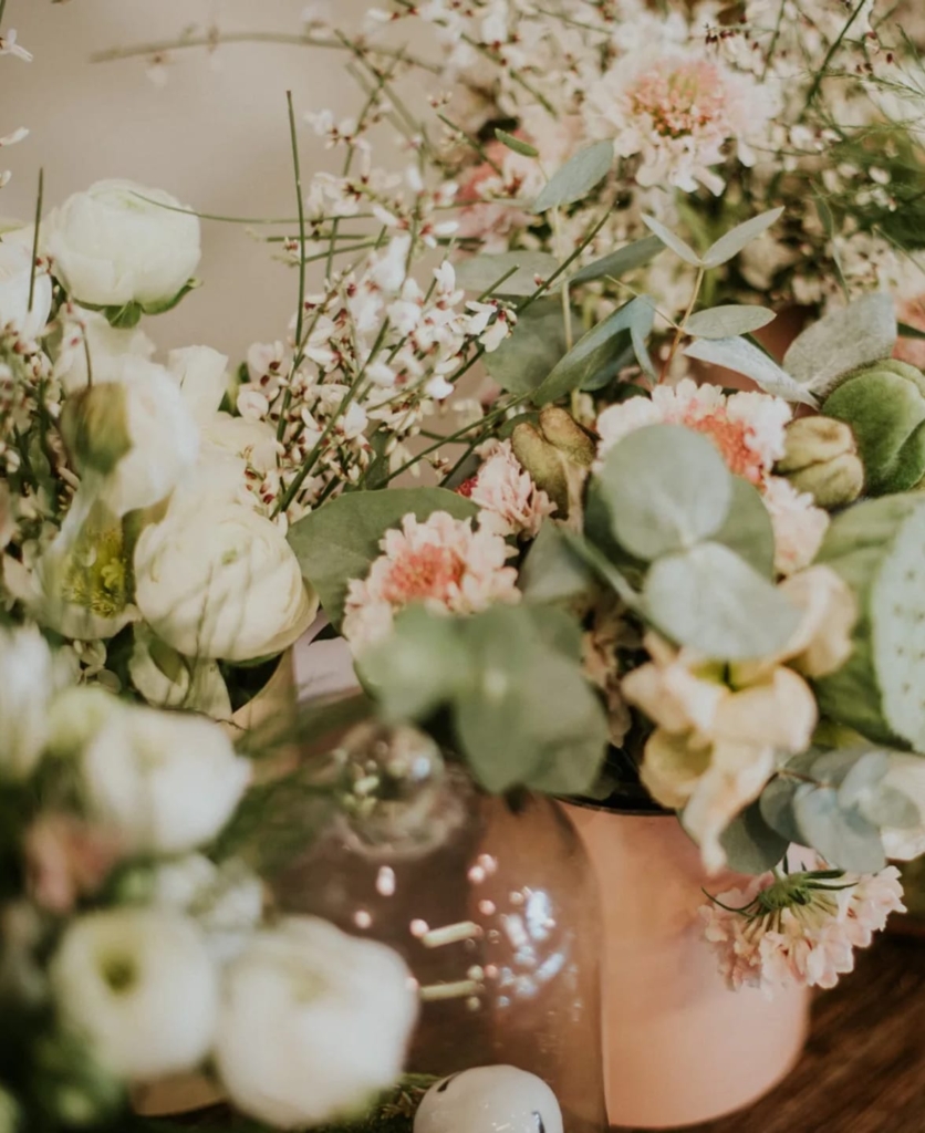 Composition de table aux chandelles avec fleurs blanches, lotus et vases cuivrés